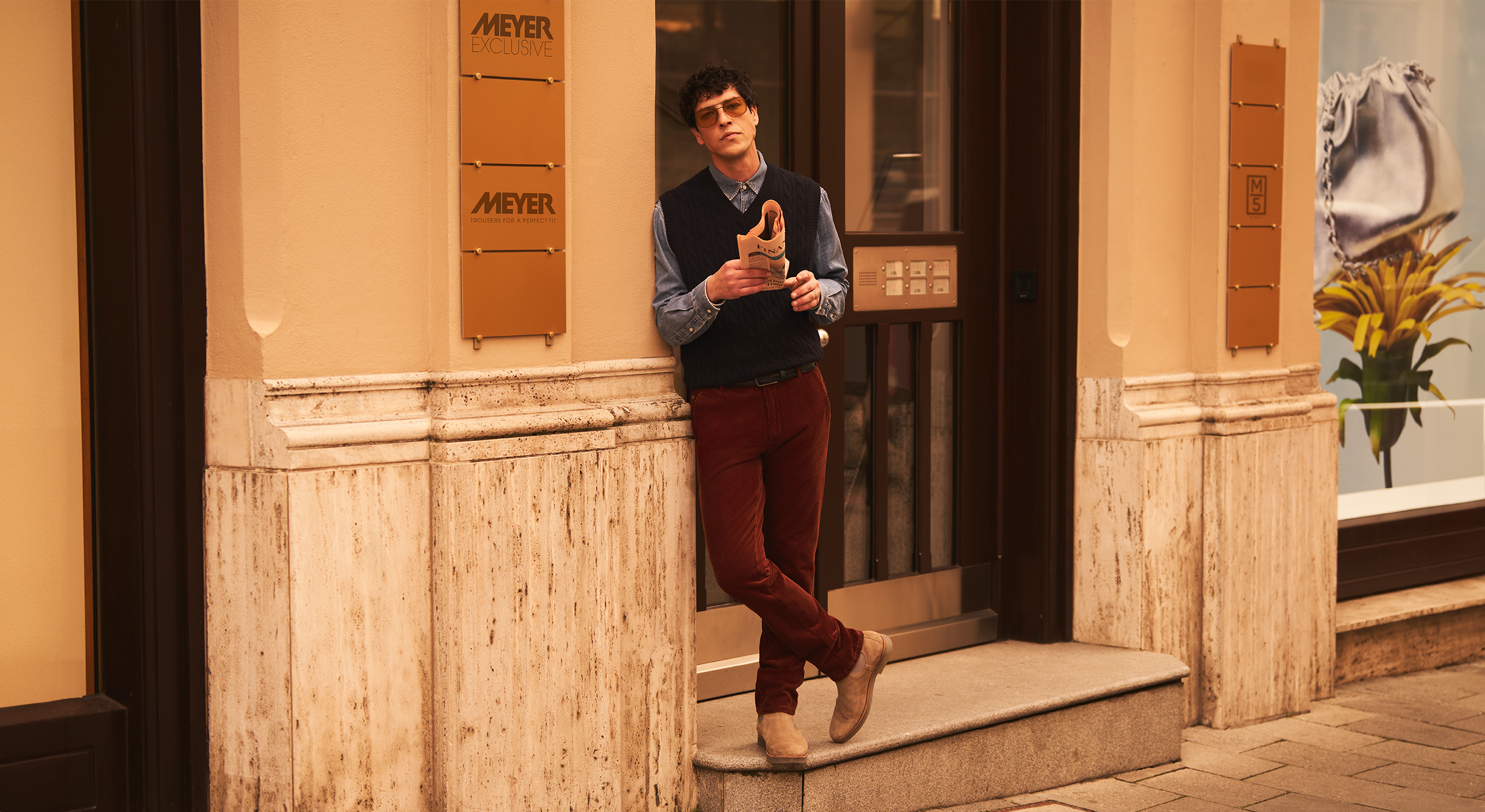 Man standing on a staircase in an urban setting with a building facade in the background